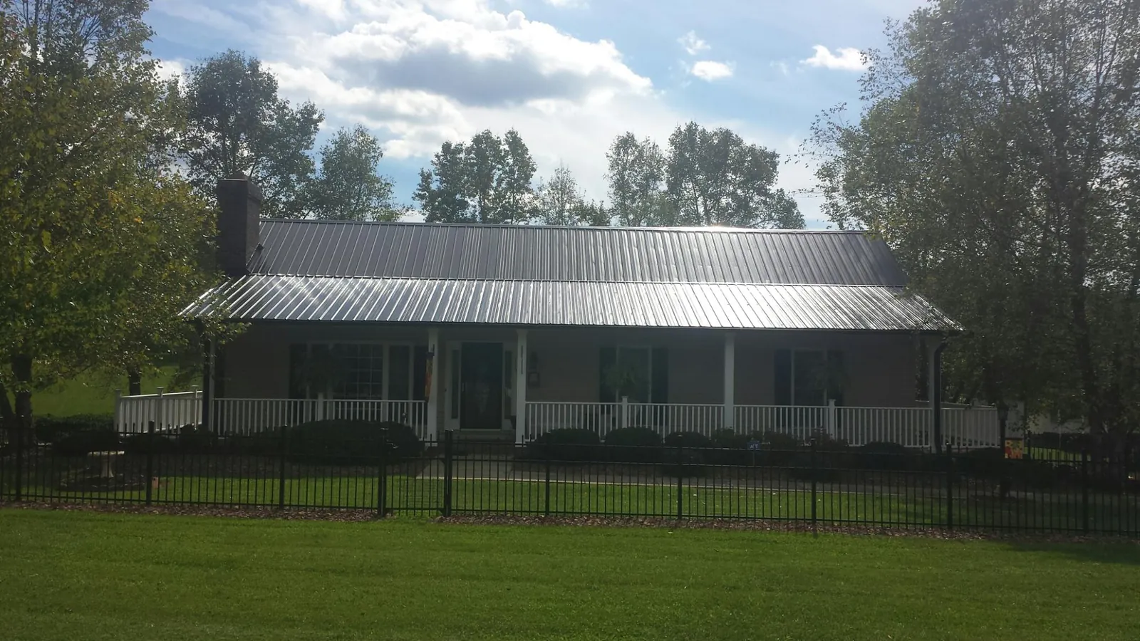 Gray metal roof on a brick ranch with a full width front porch — Gutter Guard Installation work by our crew in Berlin